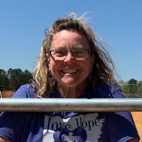 Profile photo of Sara Allen, woman with glasses and blond hair agains the blue sky background